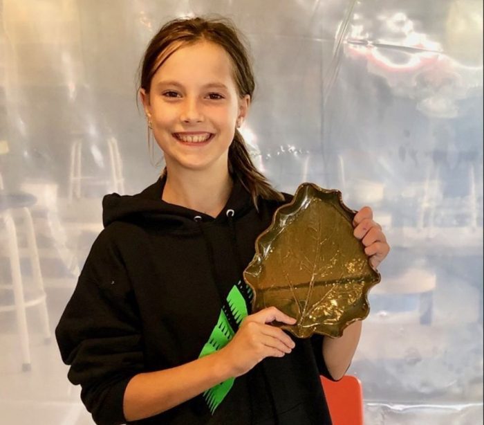 young student showing off finished hand built clay pieces
