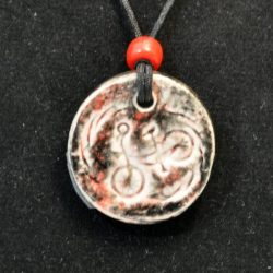 Carved black and red pendant with a bicycle by Ann Hobday