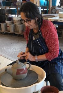 Cathy Allen decorating a teapot on the wheel