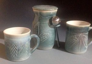 Coffee grounds jar and two mugs carved with leaves and glazed in a variety of greens - Lillian Forester