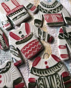 Holiday ornaments cut in sweater shaped and painted in various patterns and colours - Cathy Allen