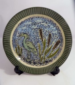 Carved plate featuring a blue heron in cattails - Cathy Allen