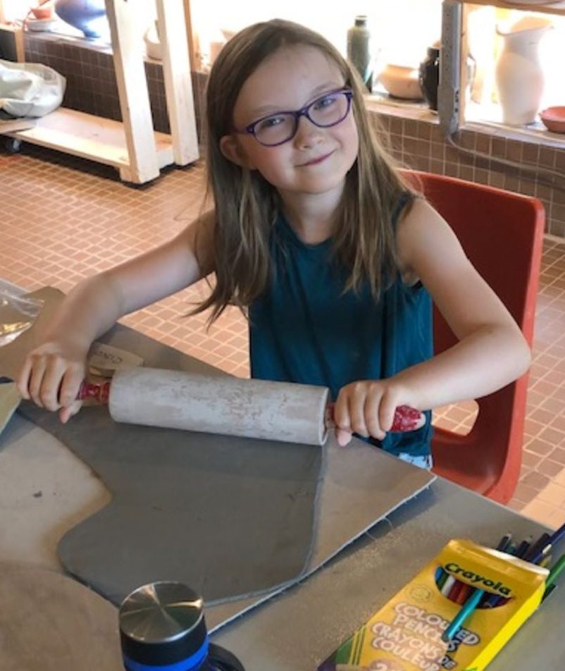 Child rolling out clay during clay & crafts camp