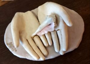 sculpture of two outstretched hands holding a sea shell