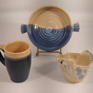 A mug, small handled casserole and bird shaped pitcher in Heather Brooks' cream and blue glaze combination